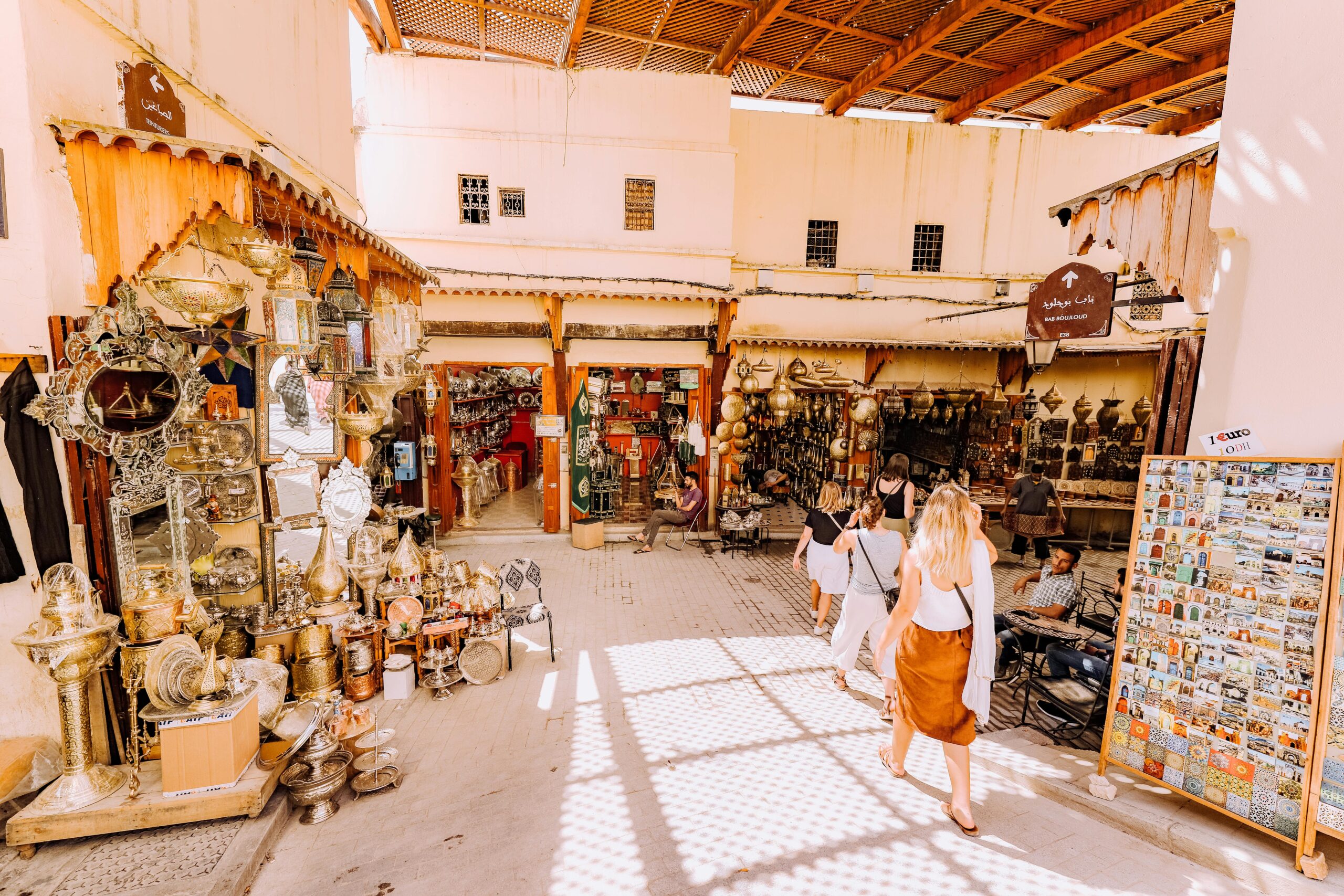 Lively market scene in a traditional Middle Eastern bazaar with tourists exploring shops.